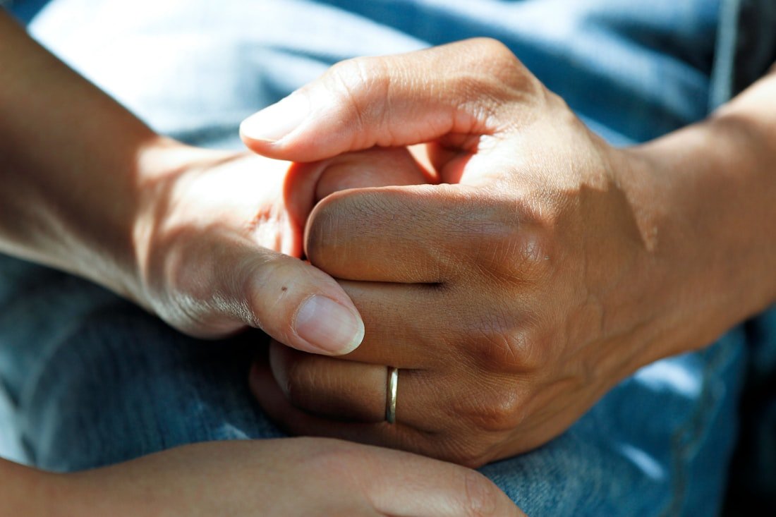 Two people holding hands gently in a warm, reassuring moment