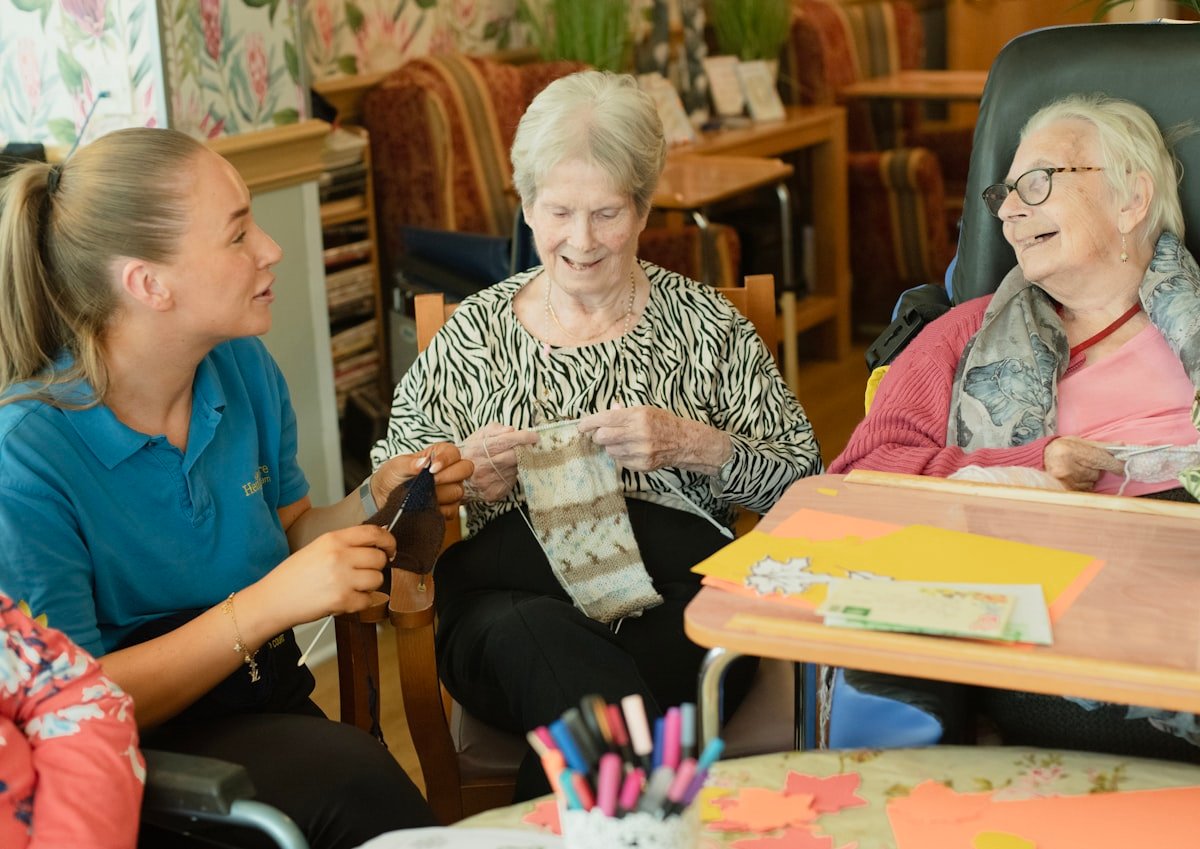 A Bloom caregiver laughing with two older women during an afternoon activity